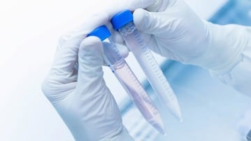 Cancer research laboratory, hands of scientist holding up test tubes with cells in solution