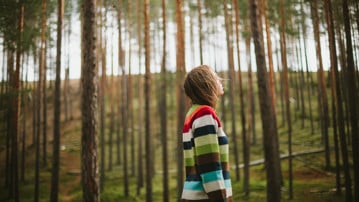 En person står i en tallskog