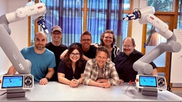 Gruppen Collaborative Robotics Lab som poserar med två robotarmar från ABB