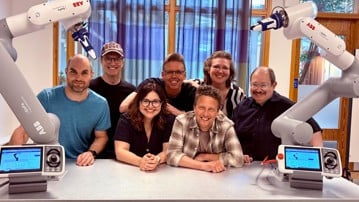 Gruppen Collaborative Robotics Lab som poserar med två robotarmar från ABB