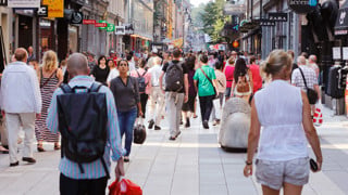 Sommardag på gågatan Drottninggatan mellan Mäster Samuelsgatan och Kungsgatan i Stockholm, Sverige, med folk i rörelse. Genrebild från Mostphtos för att illustrera stad, människor, trängsel, terrorism.