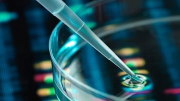 Pipett som droppar i vätska i petriskål, DNA-profiler i bakgrunden