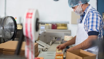 Man packaging vegan cheese in warehouse