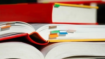 Books are piled with bookmarks. Genrebild från Mostphotos.