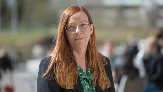 Britt-Inger Keisu. En kvinna med rött hår och glasögon står utomhus i solen.