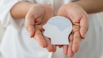 Mental health awareness, human hand care and support hold white paper head and glowing brain with physical and mental health, wellbeing, brain health, psychological support, healthcare and mindfulness