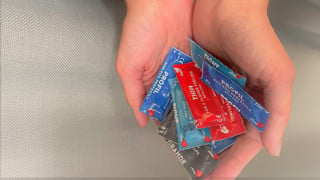Två händer som håller i kondomer. Ska symbolisera att Studenthälsan erbjuder gratis testning av sexuellt överförbara infektioner samt erbjuder gratis kondomer.
