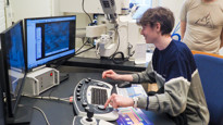 Gymnasieeleven Simon Blind zoomar in på detaljerna av en fluga med ett av universitetets sofistikerade elektronmikroskop vid UCEM. Nils Hauff är staff scientist vid UCEM.
/
High school student Simon Blind zooms in on the details of a fly using one of the university's sophisticated electron microscopes at UCEM. Nils Hauff is a staff scientist at UCEM.
