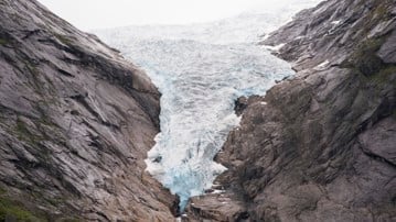 Glaciär som tränger ned mellan två bergssidor