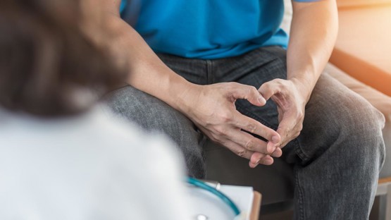 Male patient having consultation with doctor or psychiatrist who working on diagnostic examination on men's health disease or mental illness in medical clinic or hospital mental health service center.