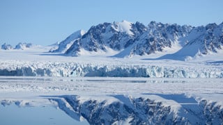 Spegling av berg i vatten på Svalbard.