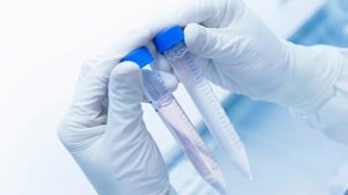 Cancer research laboratory, hands of scientist holding up test tubes with cells in solution