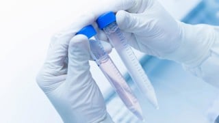 Cancer research laboratory, hands of scientist holding up test tubes with cells in solution