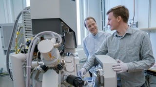 – Erik Olof WikLund, konstnär och examinerande masterstudent vid Konsthögskolan, Umeå universitet
– Nils Hauff, staff scientist, Umeå Centre for Electron Microscopy, Umeå universitet, SciLifeLab 

Erik Olof Wiklund, artist, and Nils Hauff, staff scientist at UCEM, has been using a FIB-SEM (focused ion beam-scanning electron microscope) to carve out the microscopic Dala horse from a piece of platinum. Photo: Mattias Pettersson, Umeå University.