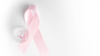 Breast cancer research concept, glass petri dish and pink awareness ribbon isolated on white background. Banner