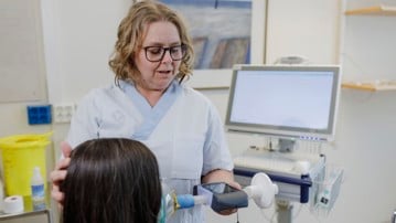 Forskningssjuksköterskan och studiekoordinatorn Nina Sundqvist mäter lungfunktionskapaciteten med hjälp av en spirometer.