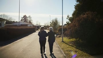 Äldre och yngre kvinna promenerar bort från fotografen