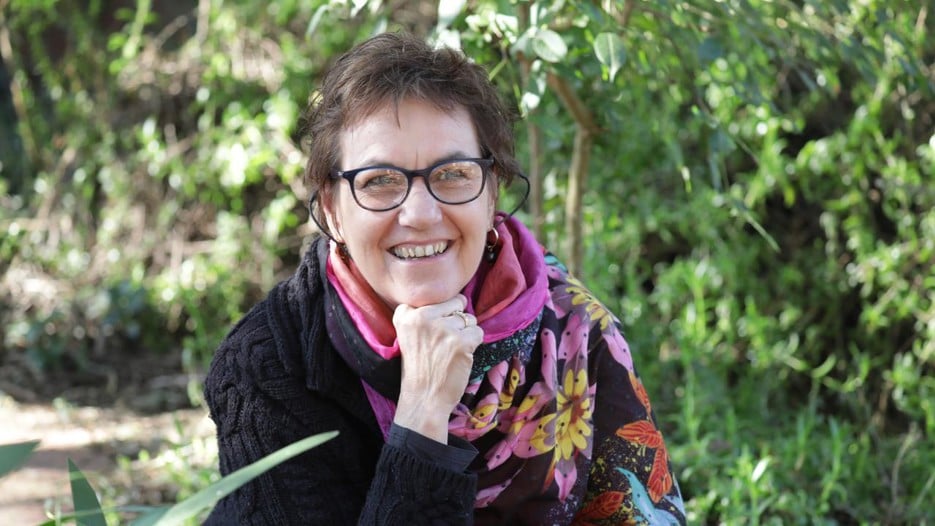 A woman wearing glasses is sitting on a bench.