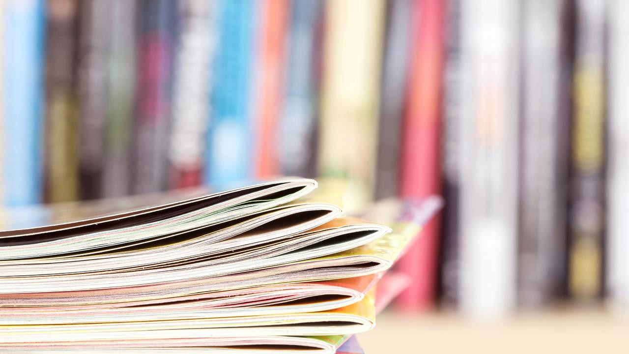 Close up edge of colorful magazine stacking with  blurry bookshelf background for publication and publishing concept , extremely DOF