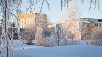 Vintercampus. Vy över förvaltningshuset och lärarutbildningshuset med dammen i förgrunden.