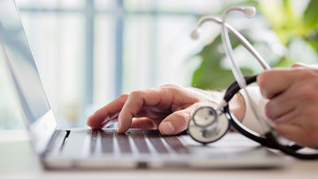 Doctor entering patient notes on a laptop in surgery