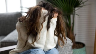 Kvinna som döljer sitt ansikte i sina händer. Ska illustrera psykisk ohälsa, ångest, oro, stress, depression, nedstämdhet eller liknande.