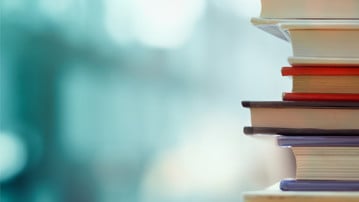 Book stack in the library room and blurred bookshelf, business and education background