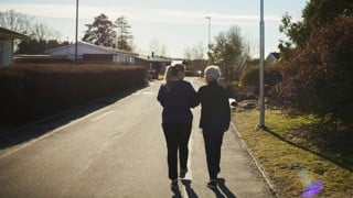 Äldre och yngre kvinna promenerar bort från fotografen