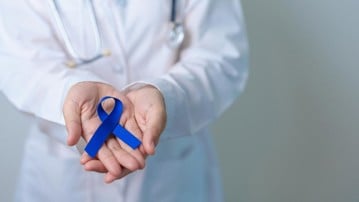 March Colorectal Cancer Awareness month, doctor with dark Blue Ribbon for supporting people living and illness. Healthcare, hope and World cancer day concept