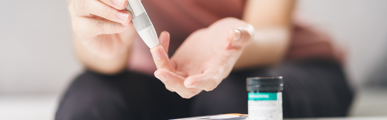 Asian woman using lancet on finger for checking blood sugar level by Glucose meter, Healthcare and Medical, diabetes, glycemia concept