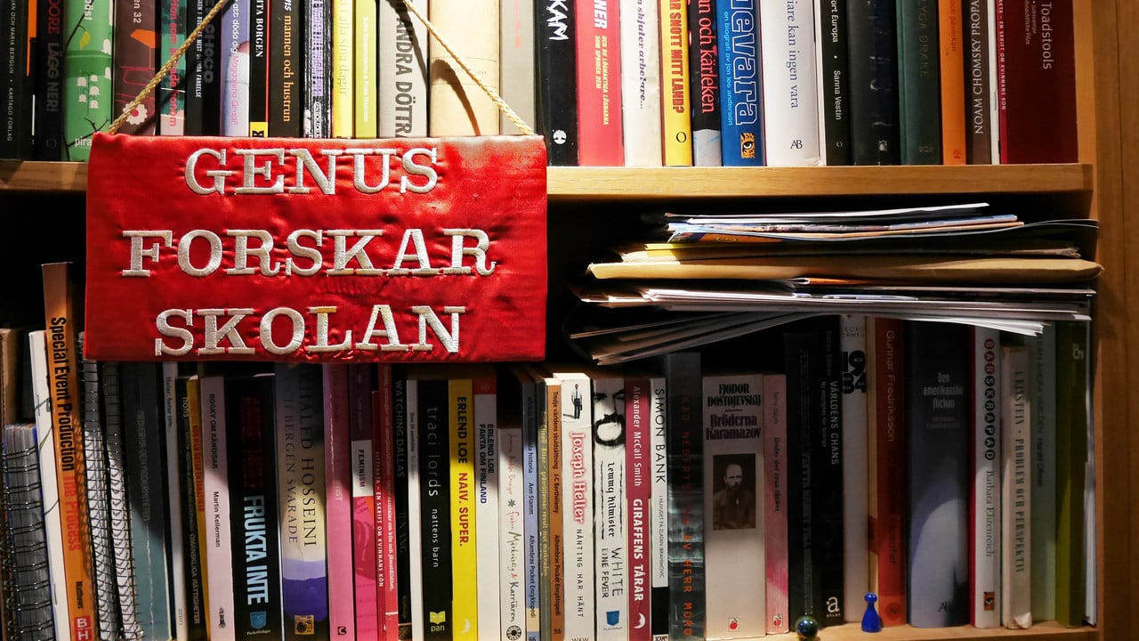 Broderad genusforskarskoleskylt på bokhylla