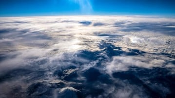 A beautiful view of the clouds and mountain under a clear sky shot from an airplane