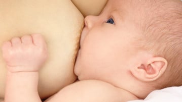 Newborn sucks mother's breast, breastfeeding, shallow DOF