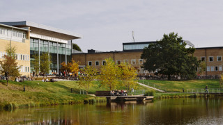 Studenter utomhus på campus. Vy över dammen och Lindellhallen.