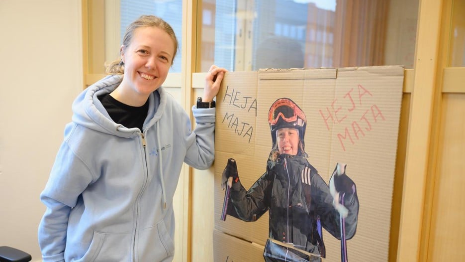 A woman standing next to a poster of herself skiing.