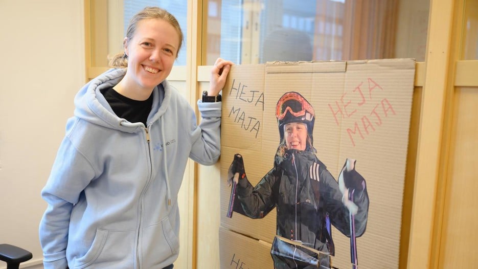 A woman standing next to a poster of herself skiing.