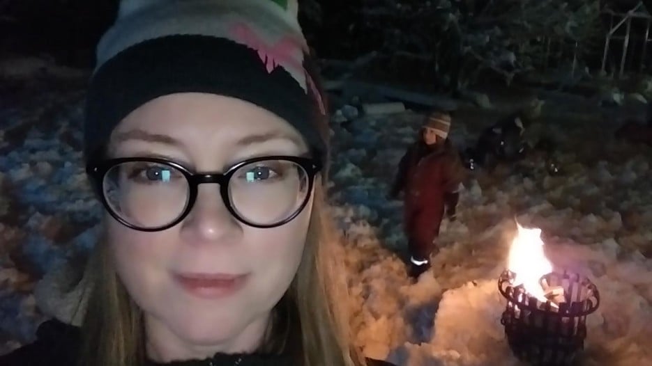 Linda Lundmar, föreståndare vid den arktiska forskarskolan vid Arcum, är utomhus vid en grillkorg med sitt barn en mörk vinterkväll