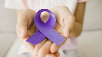 Hands holding purple ribbon, Alzheimer's disease, Pancreatic cancer, Epilepsy awareness, world cancer day, cancer survivor day, concept