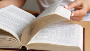 Närbild på händer som bläddrar i en bok.