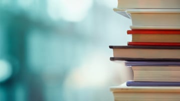 Book stack in the library room and blurred bookshelf, business and education background