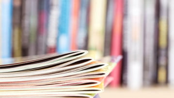Close up edge of colorful magazine stacking with  blurry bookshelf background for publication and publishing concept , extremely DOF