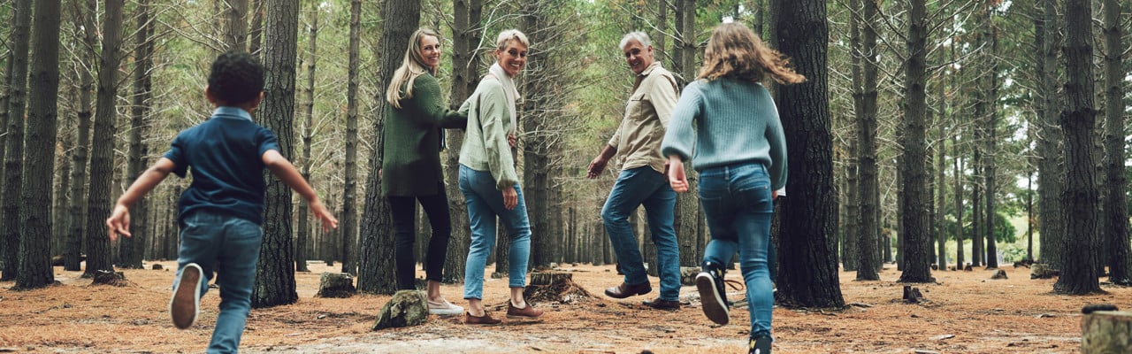 Forest, big family and adventure with children, parents and grandparents walking in nature for outdoor hiking, fun and trees on wellness vacation. Running kids, travel and happy man and women in woods