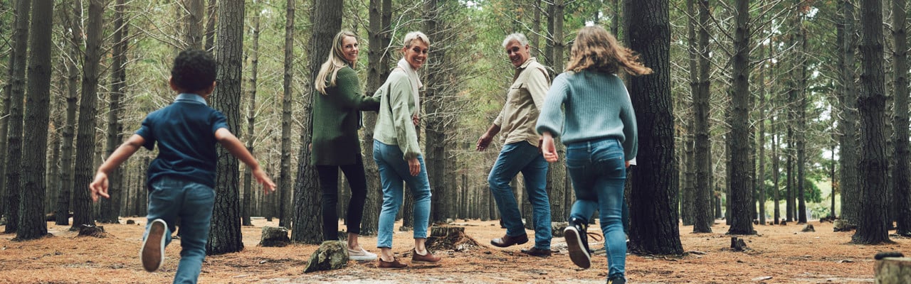 Forest, big family and adventure with children, parents and grandparents walking in nature for outdoor hiking, fun and trees on wellness vacation. Running kids, travel and happy man and women in woods