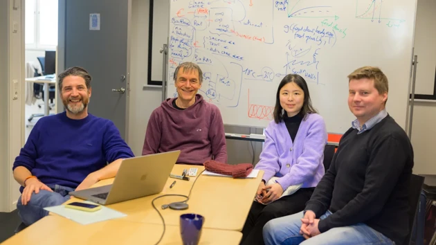 Olivier Keech, Sebastian Diehl, Yun-Ting Jang och Jonas Westin sitter vid ett konferensbord och ler mot kameran. Bakom dem finns en whiteboard med skisserade projektplaner. 