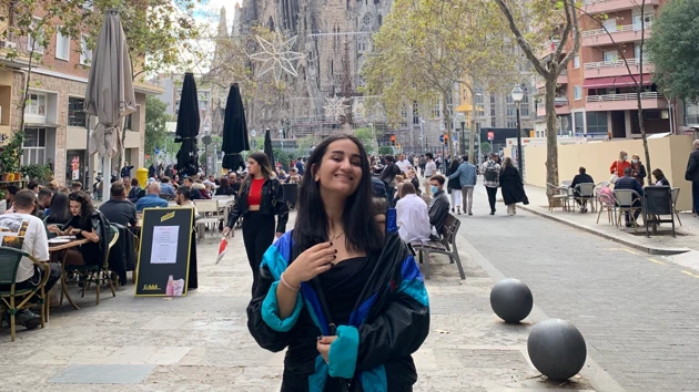 En av universitetets studenter blickar ut över en utländsk stad med färgglada byggnader och en flod.