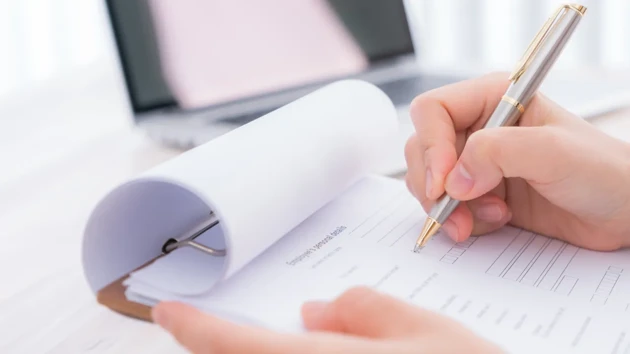 Hand with pen filling a form