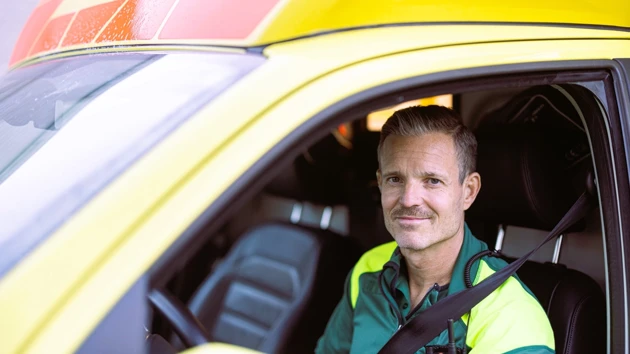 En man i gul väst sitter i en gul bil