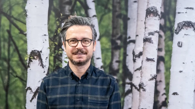 En man står framför en målning med träd