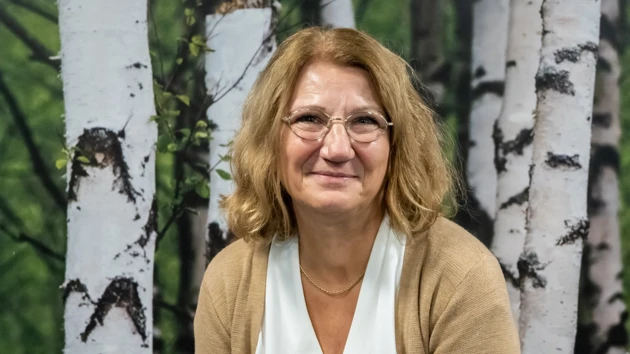 En kvinna sitter framför en målning av träd