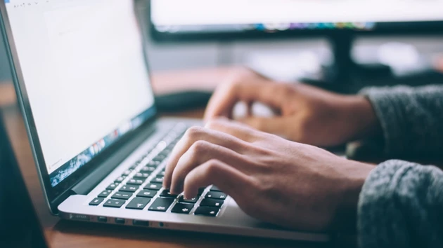 Two hands typing on a laptop.
